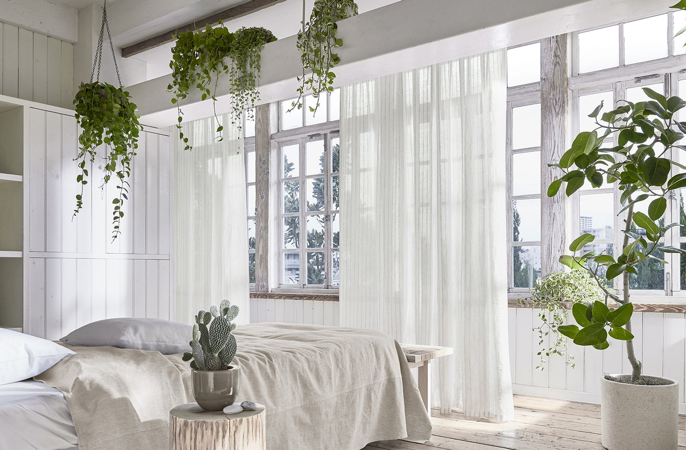 ホワイトのカーテンがかけられた寝室の写真